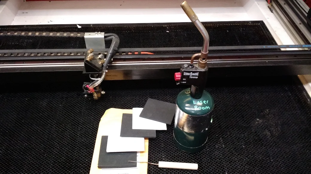 Foam samples, a testing stick, and our propane torch (with igniter trigger) on our 4x3' laser. Yes, the honeycomb bed is due for replacement soon..