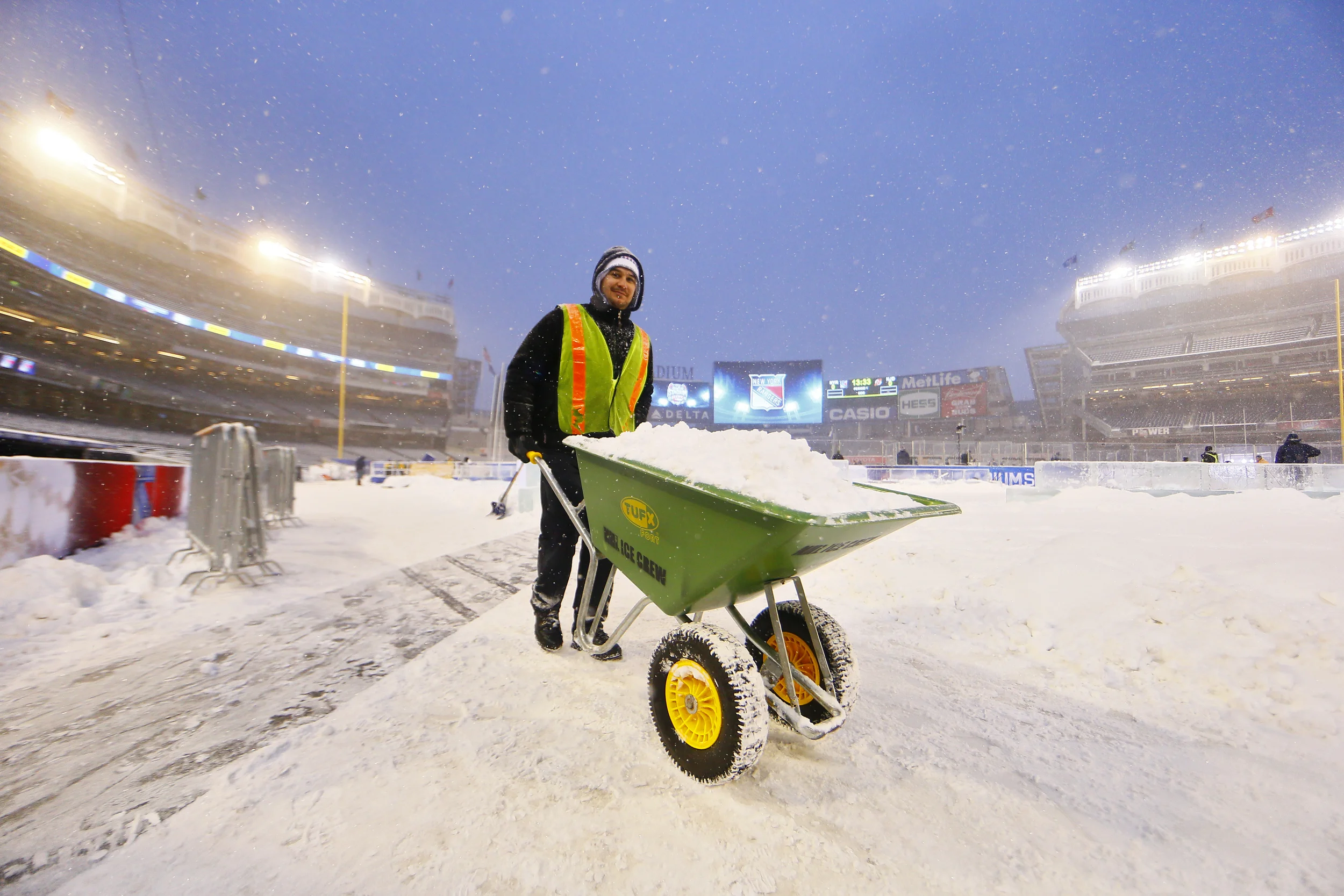 A stadium series worker transports snow away from the ice rink.jpg