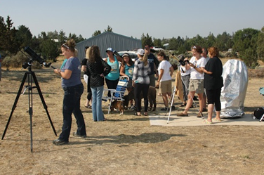 Folks age 5 to 87 gathered in chairs and on the observing field with 5, solar-filtered telescopes.