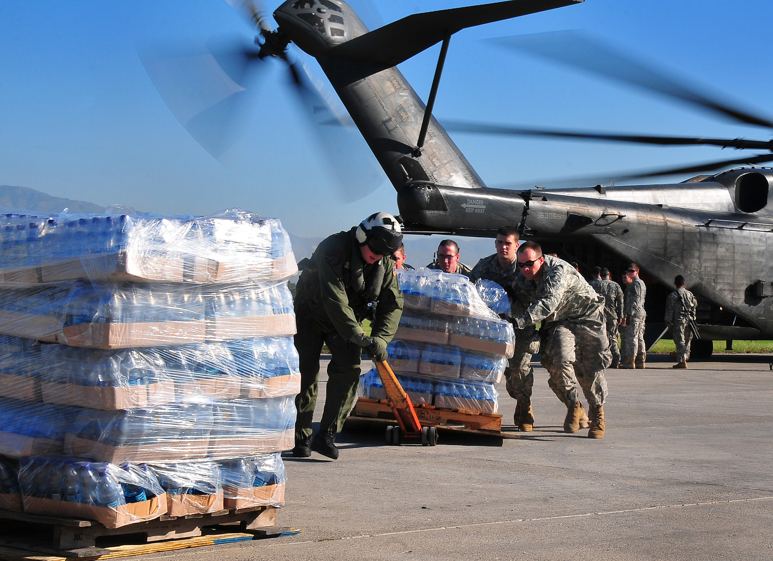 U.S. Army soldiers help the crew of a U.S. Navy MH-53E Sea Dragon helicopter from the aircraft carrier USS Carl Vinson (CVN 70) unload food and supplies at the airport in Port-au-Prince, Haiti. Daniel Barker, US Navy.