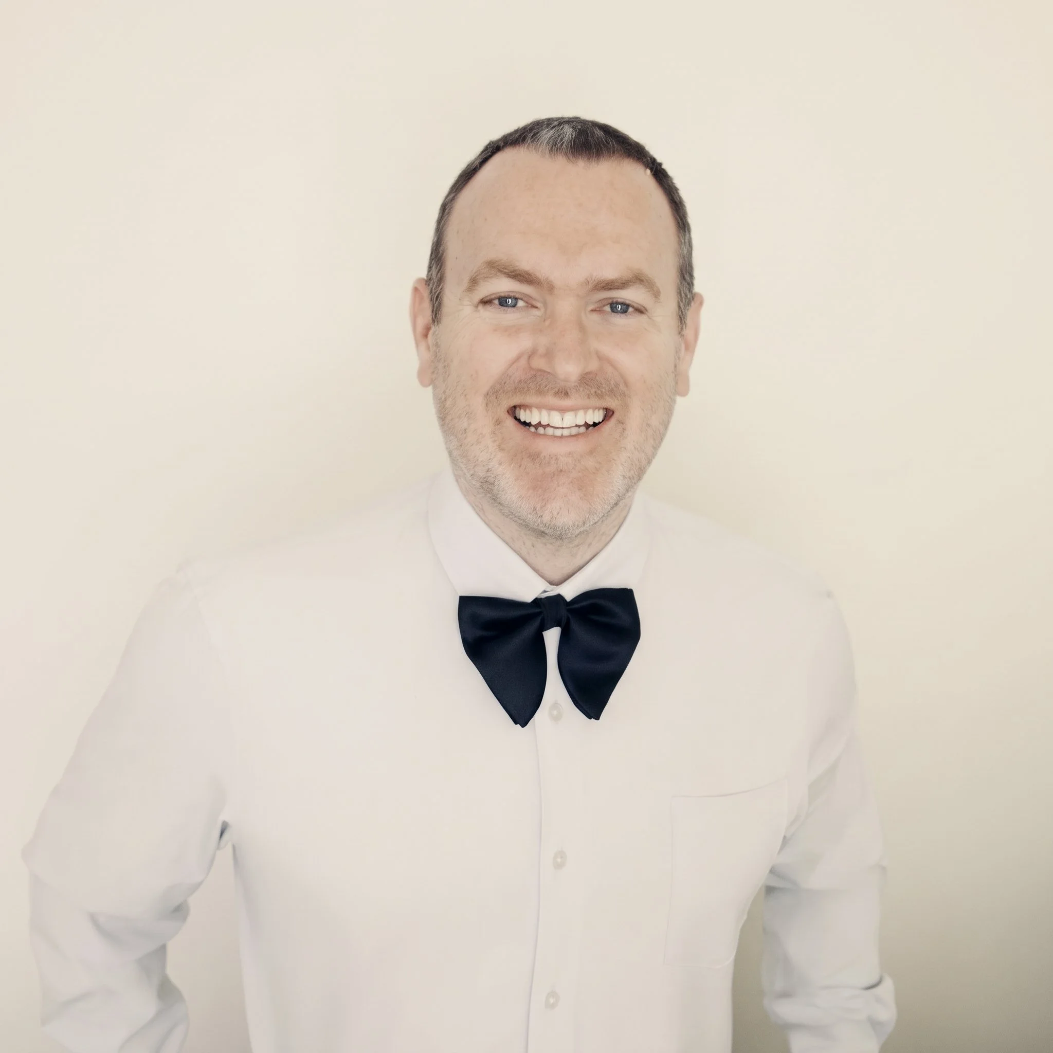 Smiling man wearing a white dress shirt and black bow tie