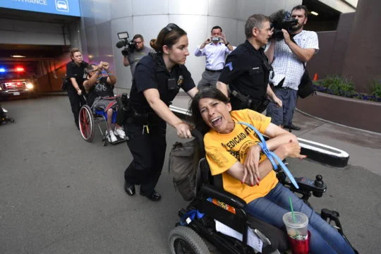ADAPT protester Lonnie Smith arrested at a sit-in at Denver US Senator Cory Gardner's office opposing GOP health care bill cuts to Medicaid (Jon Leyba/The Denver Post via AP)