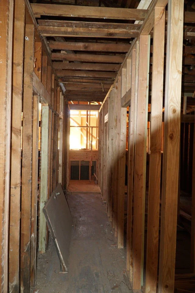 Looking north from kitchen/living through future hallway. Upper level flooring of split level addition is visible beyond.