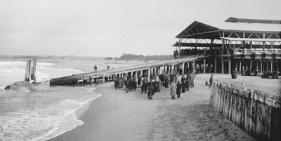 The Moss Landing Whaling Station's First Whale, January 1919. A crowd has gathered to watch the first whale, a sperm, be hauled up the slipway. The whale is visible floating in the left foreground.