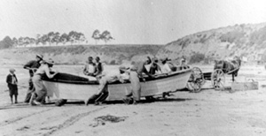 Fishermen pulling boat on rollers up China Beach,1913. This remarkable photograph was taken looking west, with present-day Park Avenue in the distance on the left, and New Brighton State Beach on the right. The box used to ship the fish is on the beach just to the right of the horse. The fish were probably shipped by train from the local railroad stop nearby. Credit: Sutton Family Collection.