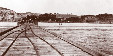 Aptos Wharf and Aptos, c. 1882. Taken during the Spreckels era looking north, this rare photograph shows the sandstone bluff that is part of today's Seacliff State Beach. The treeless hills in the distance are what we now call Aptos Village, while the buildings visible to the right of the wharf are part of Spreckels' hotel complex. The railroad tracks on the wharf were used to move cargo on small horse-drawn railcars. No railroad locomotives ever came out on the wharf. Photo Credit: Preston Sawyer Collection, University of California, Santa Cruz.