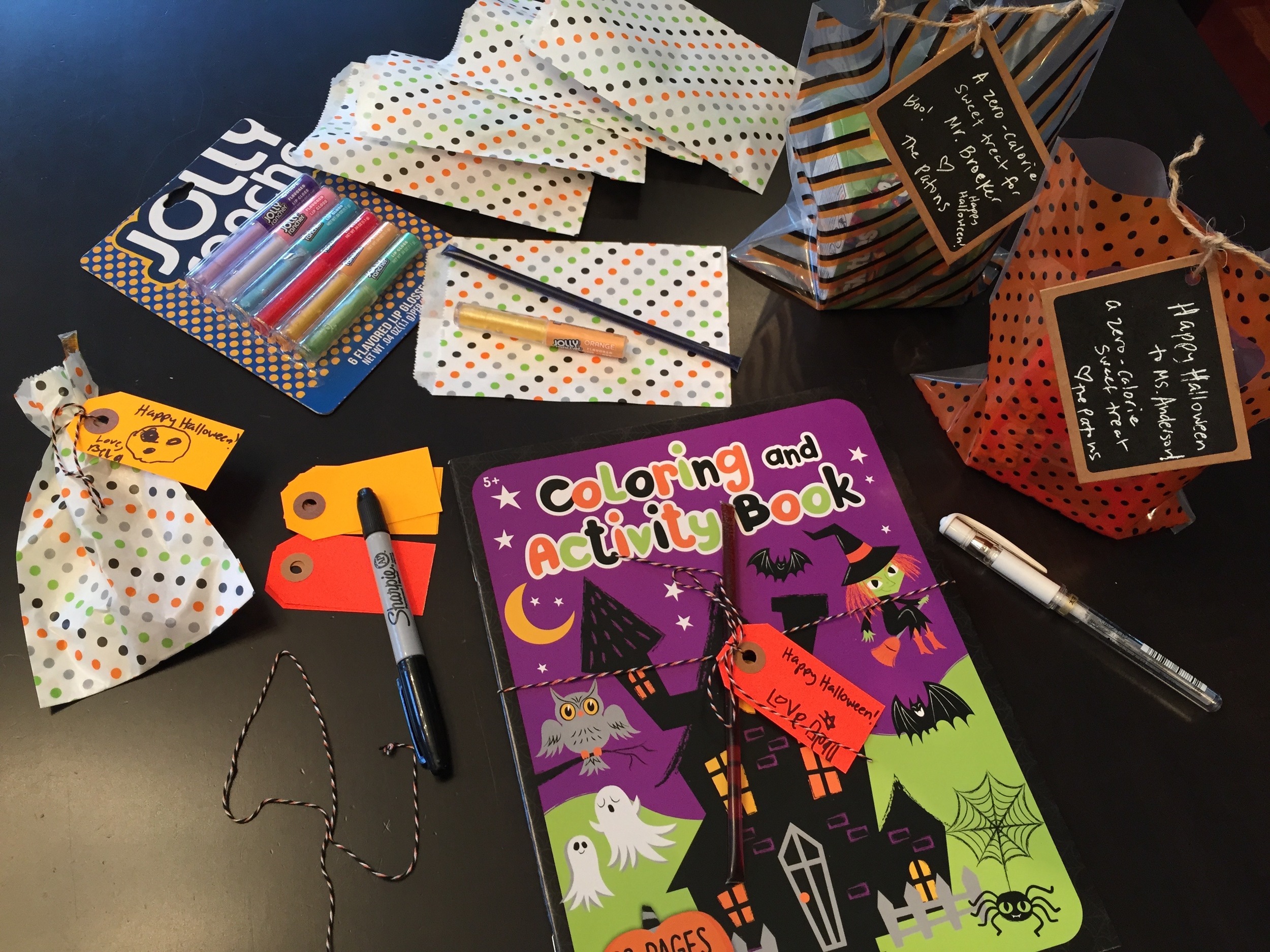 We put the teacher candles (Dollar Tree) in a cellophane bag (Target). We tied a honey stick to an activity book (book from Target, honey sticks from The Minnesota Honey Company, Tags from Brown Ink and twine from Michaels). Treat bags and lip gloss…