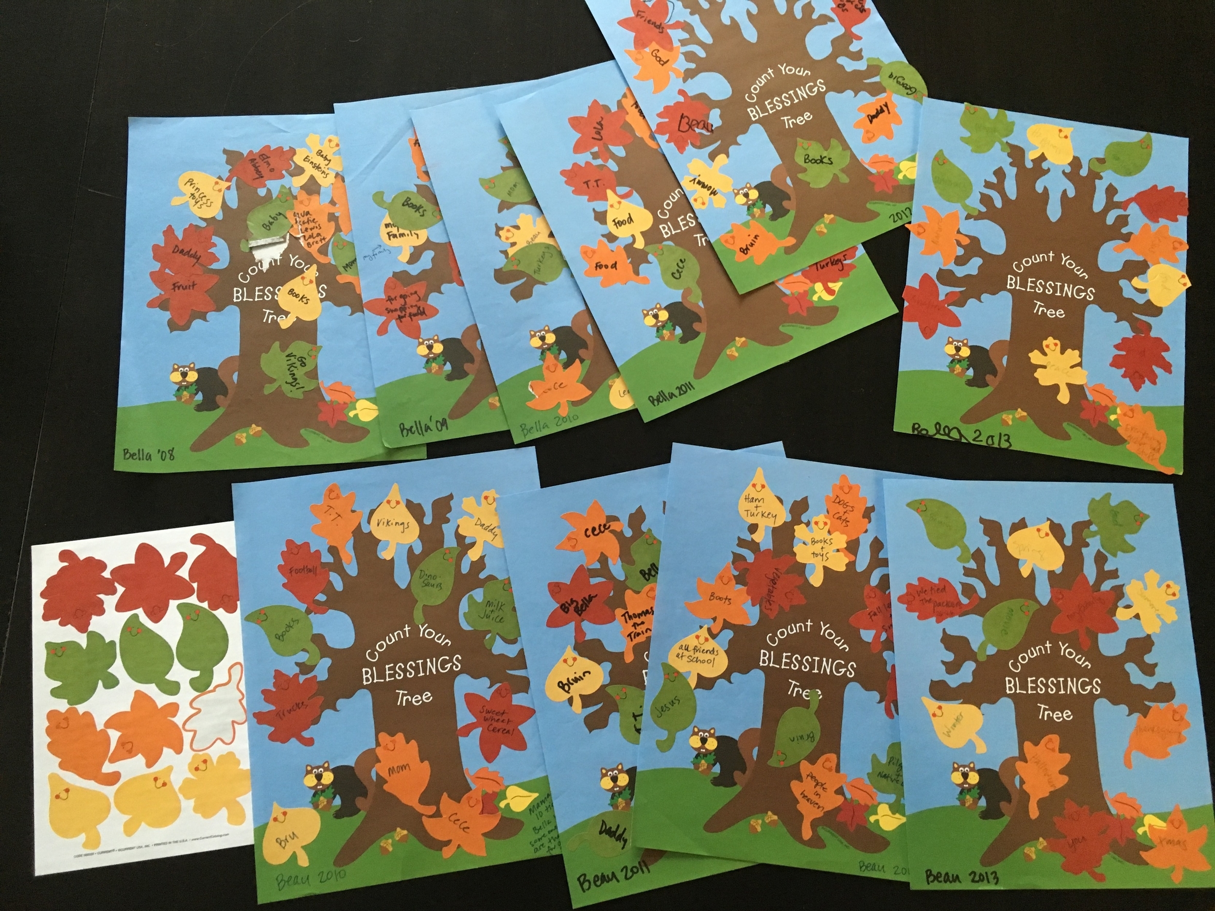 My daughter started the tradition in 2008 and was writing her own by 2012. Last year Auntie Camille brought new shiny and colorful leafs to write on - we scattered them around the table.