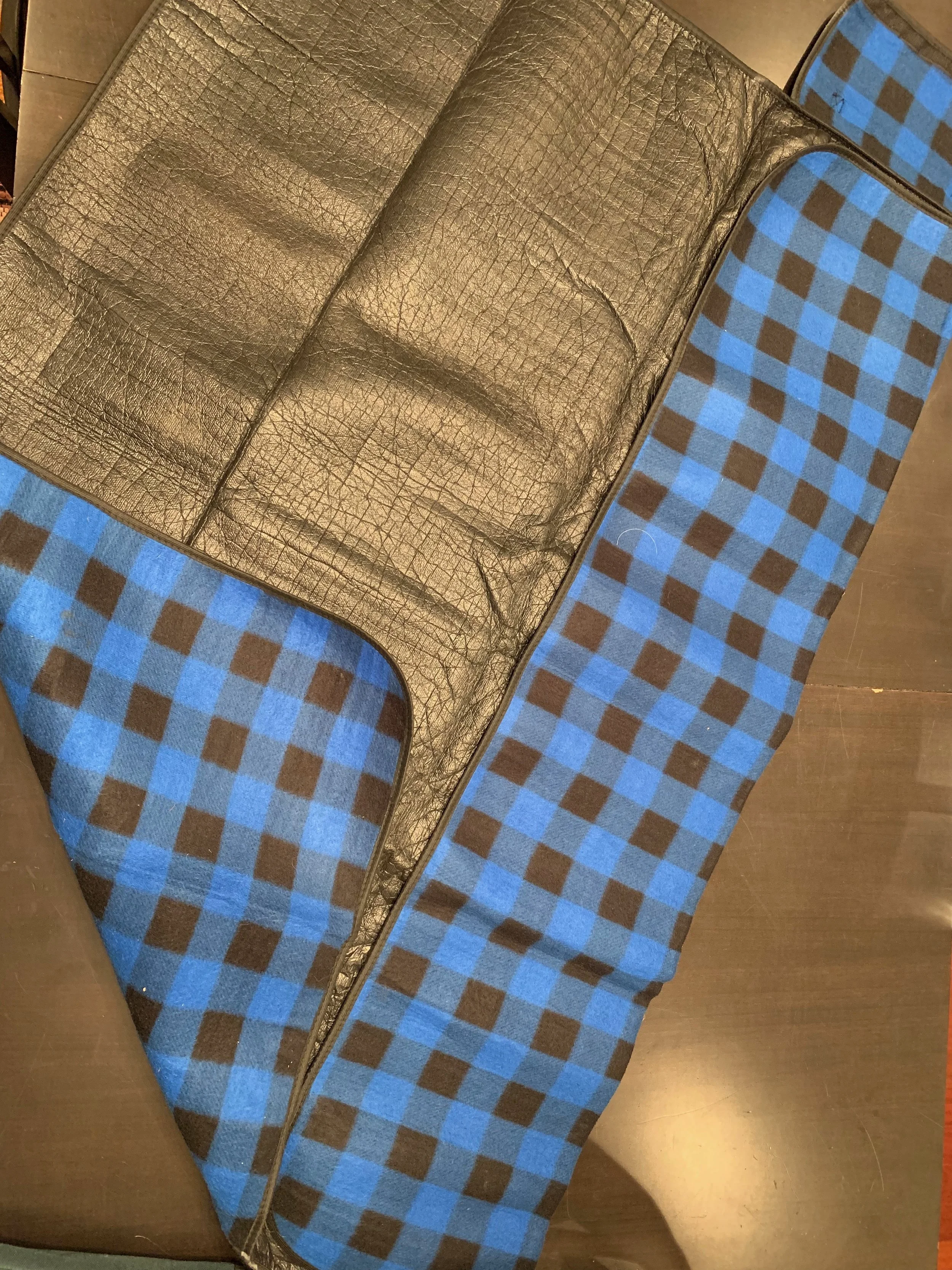 The blue/black checkered side is soft and warm. The black side is made of a nylon/plastic substance and keeps a wet ground from seeping thru. There are plenty of varieties of blankets like this available in retail stores that sell outdoor merchandise or check Amazon. This blanket measures out to 50 inches x 45 inches.