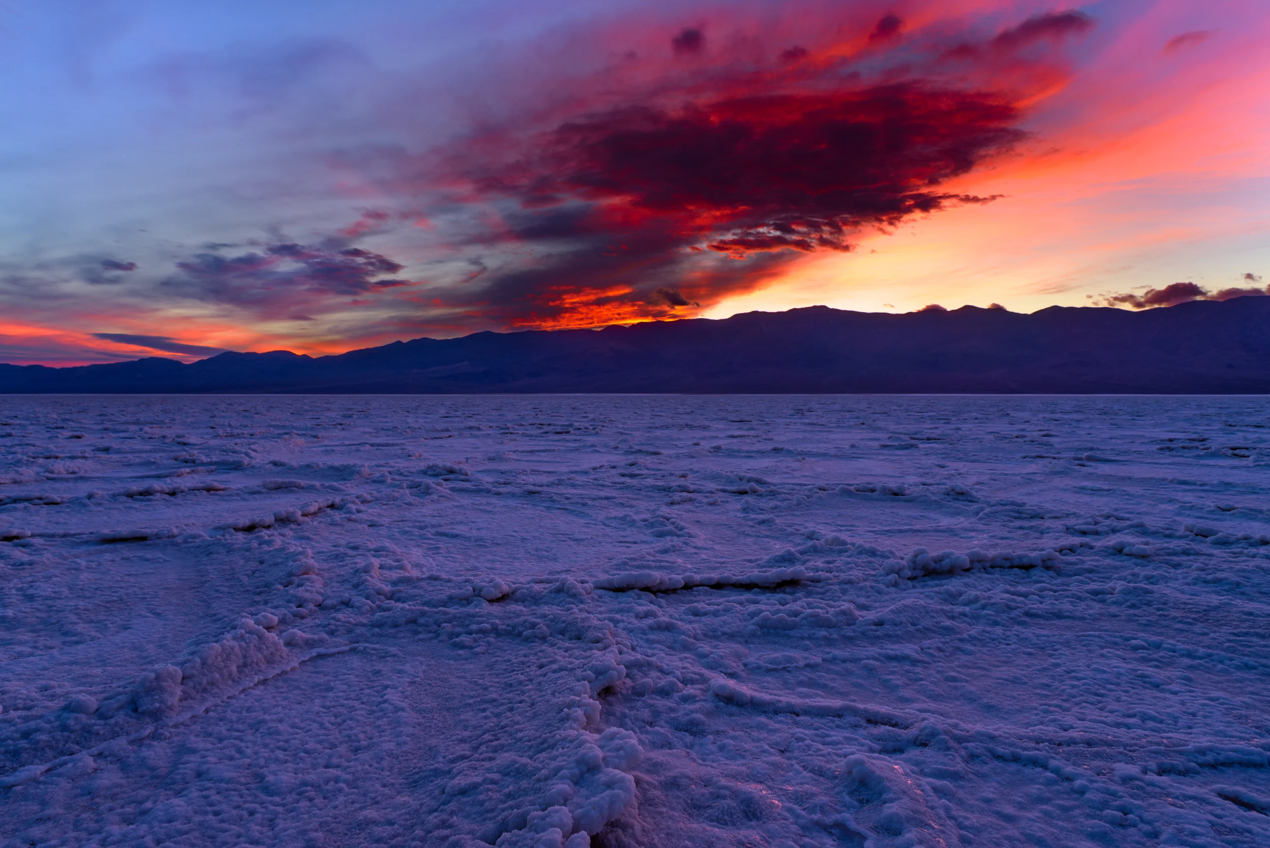 Badwater Sunset - Large thick clouds that got lit up at sunset, on the Badwater salt flats, at Death Valley.