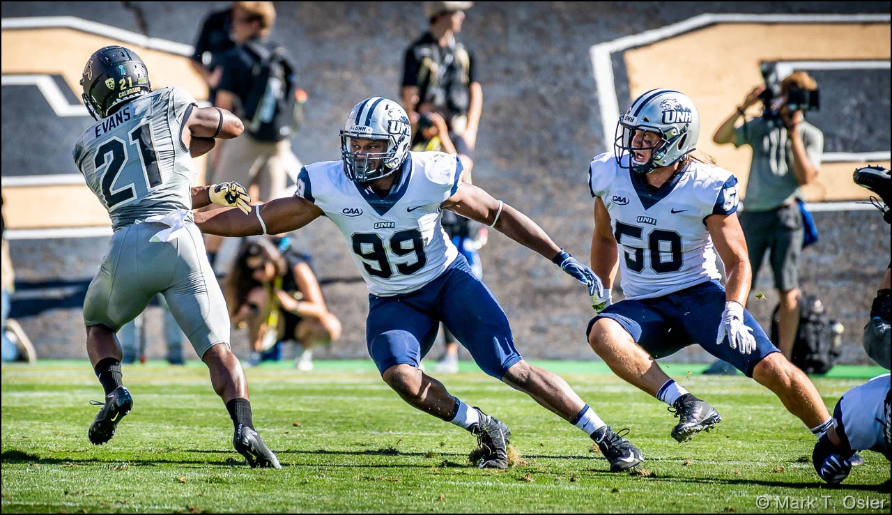 CU tailback Kyle Evans (#21) sidesteps UNH defensive end Brian Carter (#99) and linebacker Cameron Brusko (#50) for a six-yard gain early in the second quarter. UNH had trouble stopping the CU offense, which broke out to a 28-0 lead by the end of the first half.