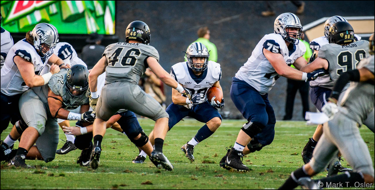 UNH running back Brandon Gallagher (#29) looks for an opening in the CU defense. CU defensive back Chase Newman (#46) defends on the play.