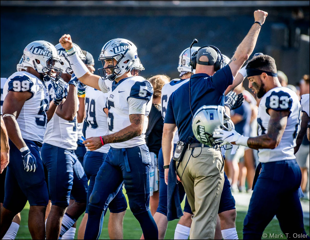 UNH quarterback Christian Lupoli (#5) and coach Garrett Gillick raise their fists to celebrate the overturning of a fumble call that would have given CU possession of the ball in the second quarter.