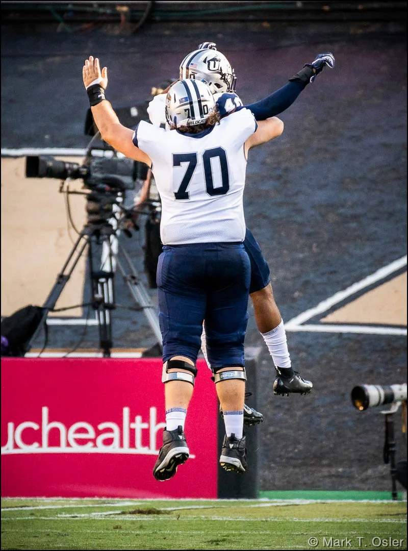 UNH offensive lineman Matt Mascia (#70) has a leaping celebration with UNH safety Pop Lacey (#40) after Lacey put UNH on the scoreboard, returning an interception 15 yards for a touchdown early in the third quarter.