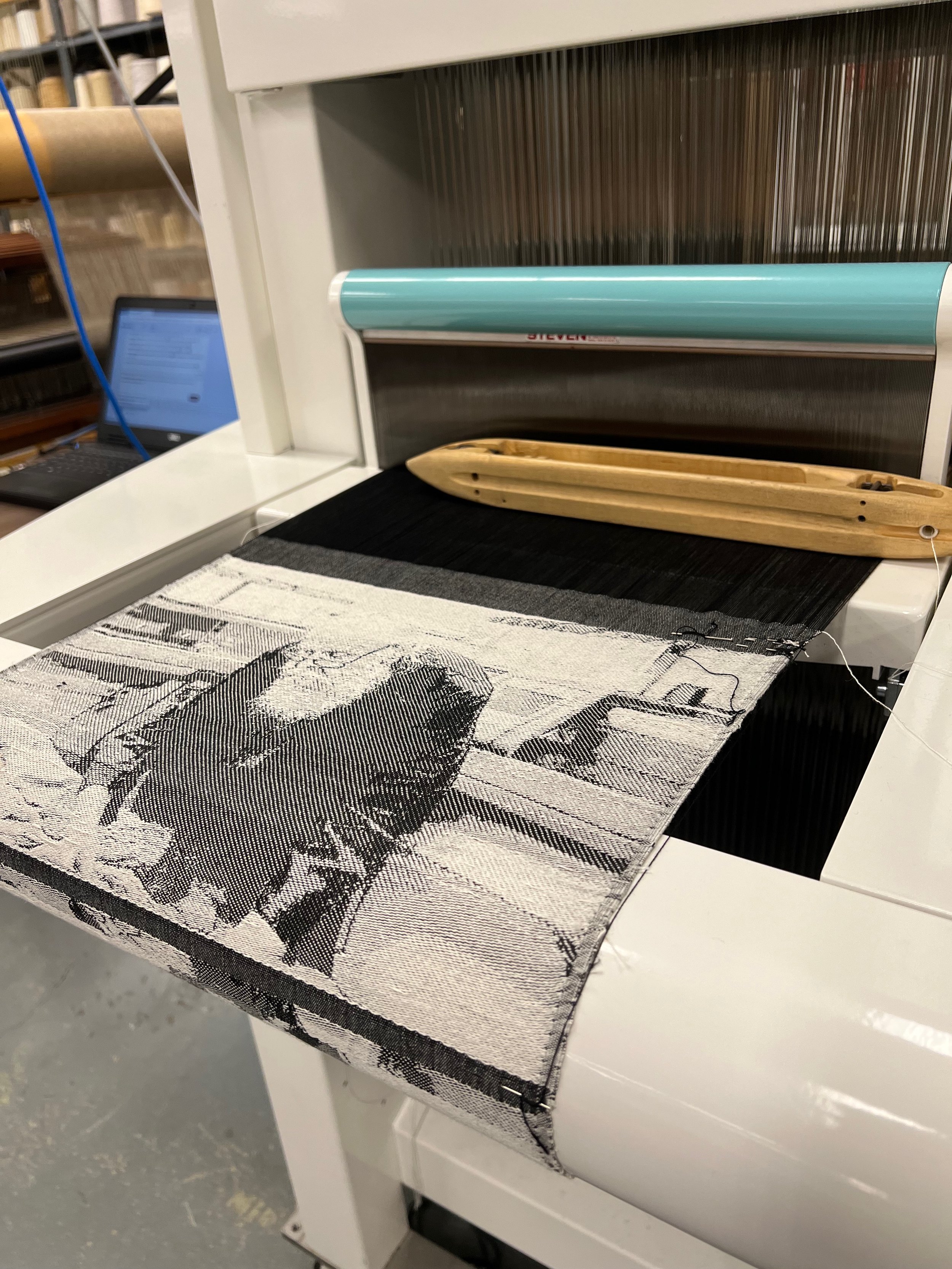 A weaving loom creating a patterned textile with a wooden shuttle.