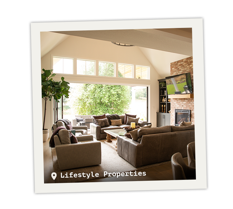 Large open air living room with couches and chairs surrounding a fireplace and TV.