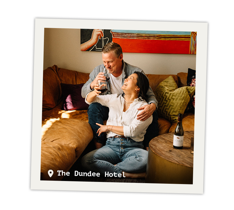 Couple lounging on a couch laughing and drinking wine.