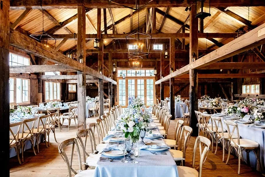 Wedding reception setup inside The Barn at Willerby near Hull, with rustic wooden beams, long banquet tables and soft countryside lighting
