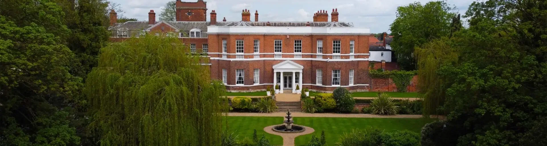 Exterior view of Bawtry Hall with landscaped gardens, red-brick facade and wedding fountain.