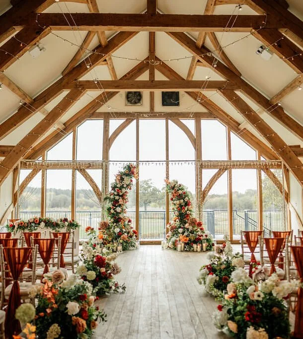 Wedding ceremony setup inside Sandburn Hall with oak beams, floral aisle décor and countryside views.