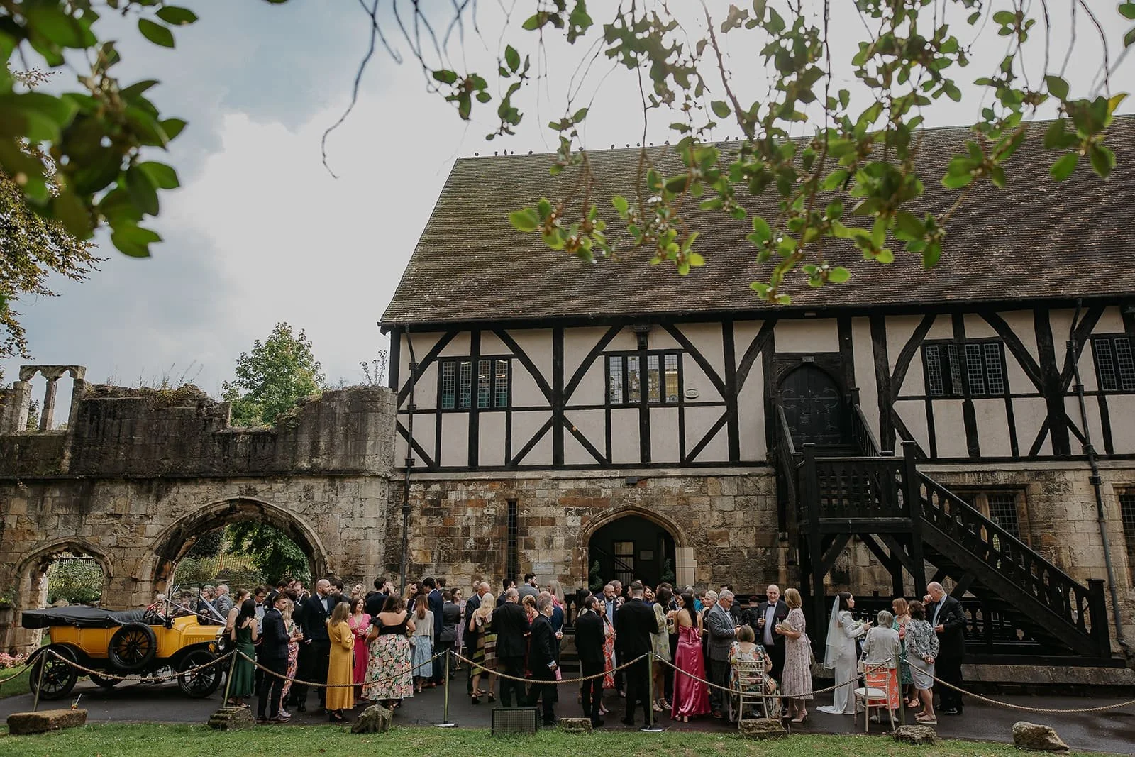 Wedding guests gathered outside The Hospitium at York Museum Gardens with the medieval building in the background.
