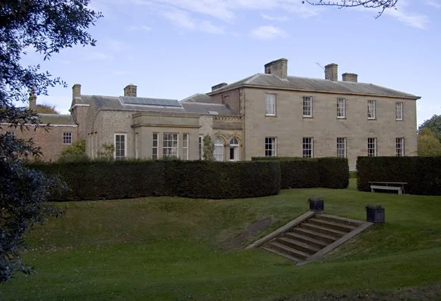 Exterior of Saltmarshe Hall in East Yorkshire, featuring elegant manor house architecture, formal lawn and landscaped gardens