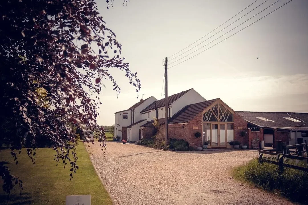 Exterior of Hornington Manor with rustic barn buildings, gravel driveway and countryside surroundings.