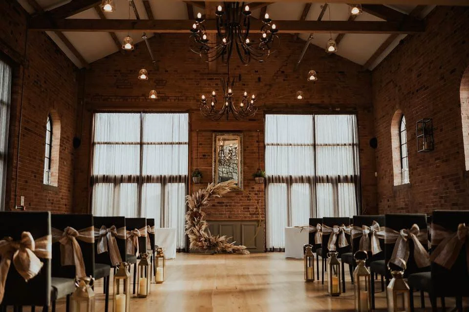 Wedding ceremony setup inside The Carriage Hall in Nottingham with chandeliers, brick walls and natural light