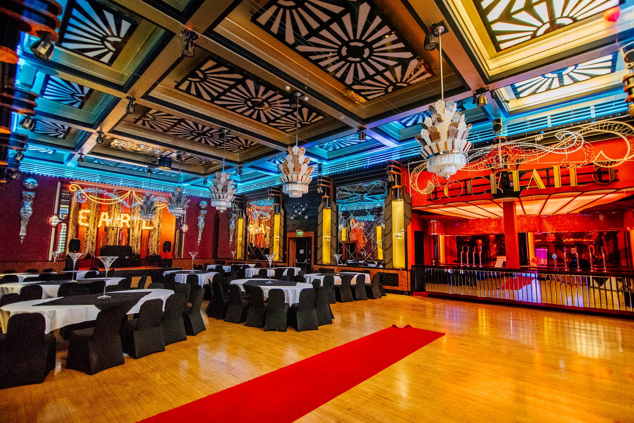Art Deco ballroom at The Earl of Doncaster Hotel with chandeliers, black chair covers and wedding reception setup.
