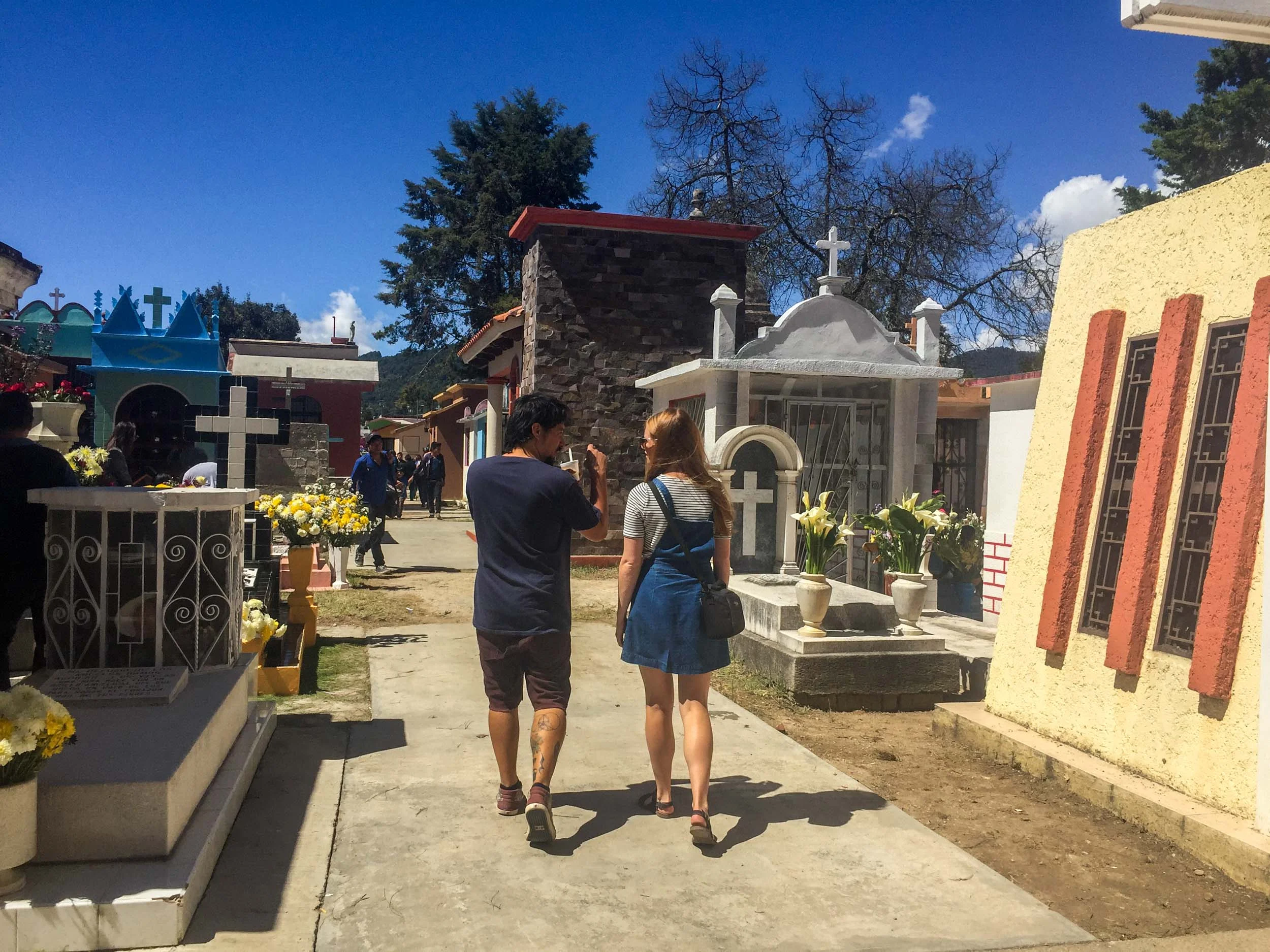 Man and woman walking and talking as they walk through cemetery in San Cristobal de las Casas, Mexico.