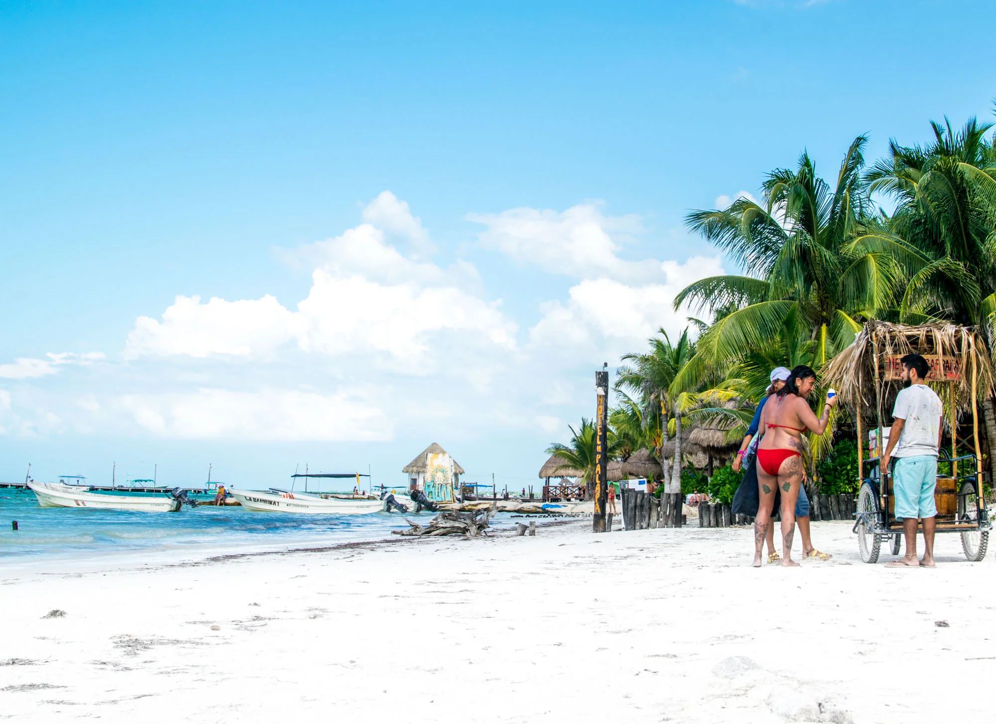Couple buying shaved coconut from a cart on the beach in Isla Holbox, Mexico.