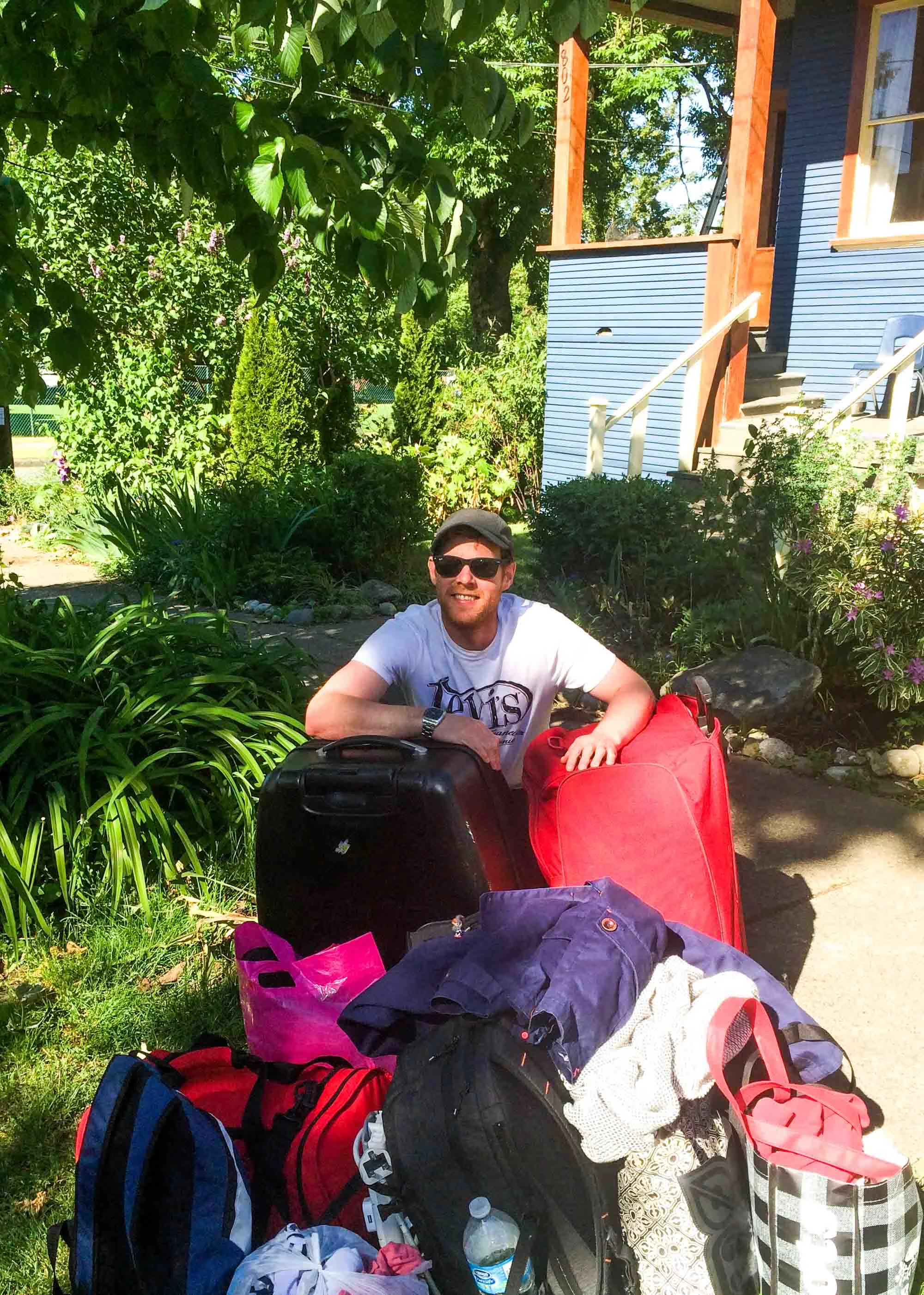 Man with a mountain of bags and suitcases, moving home after living abroad.