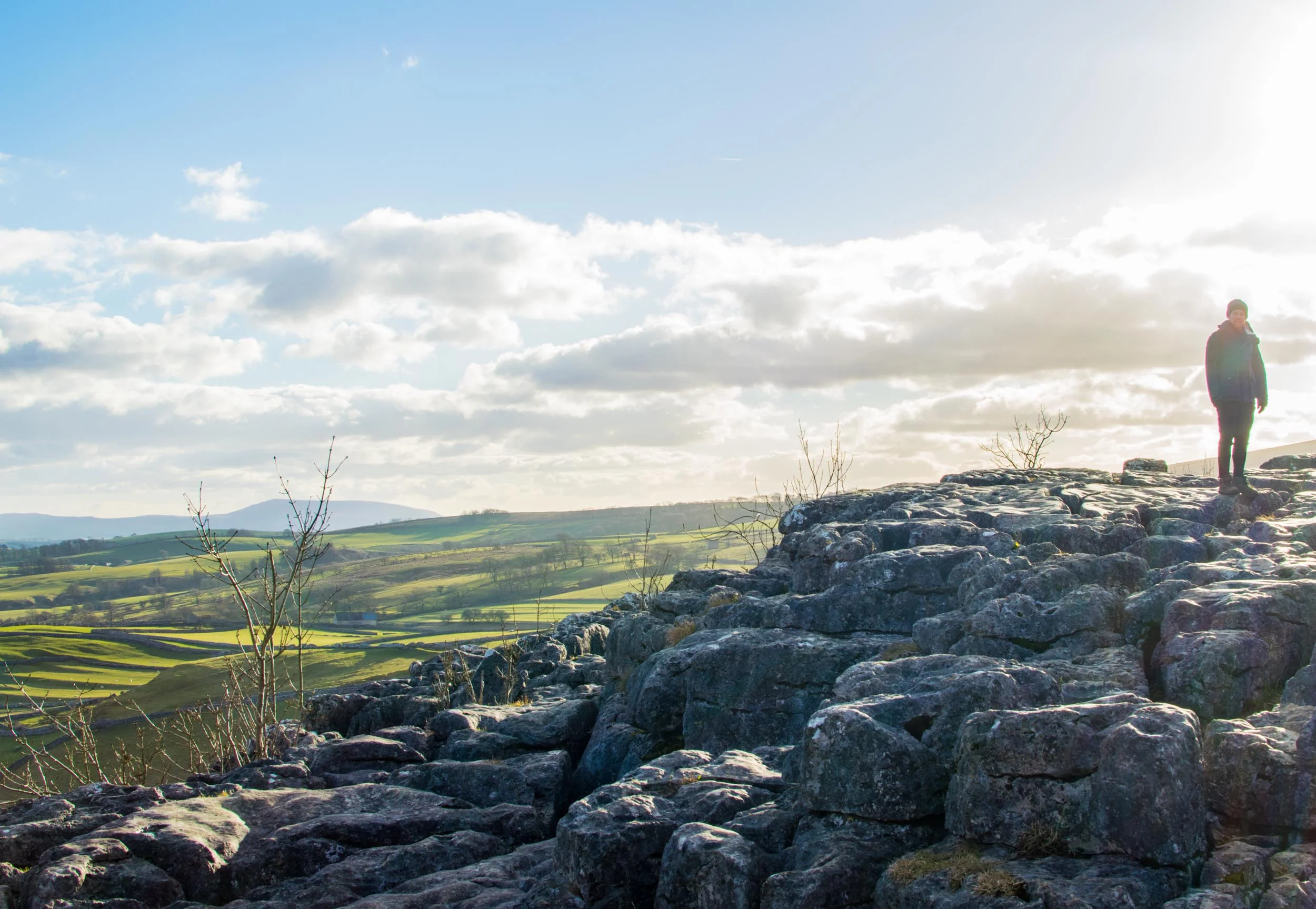 Man stood on the Limestone Pavement at Malham Cove, Yorkshire, England.