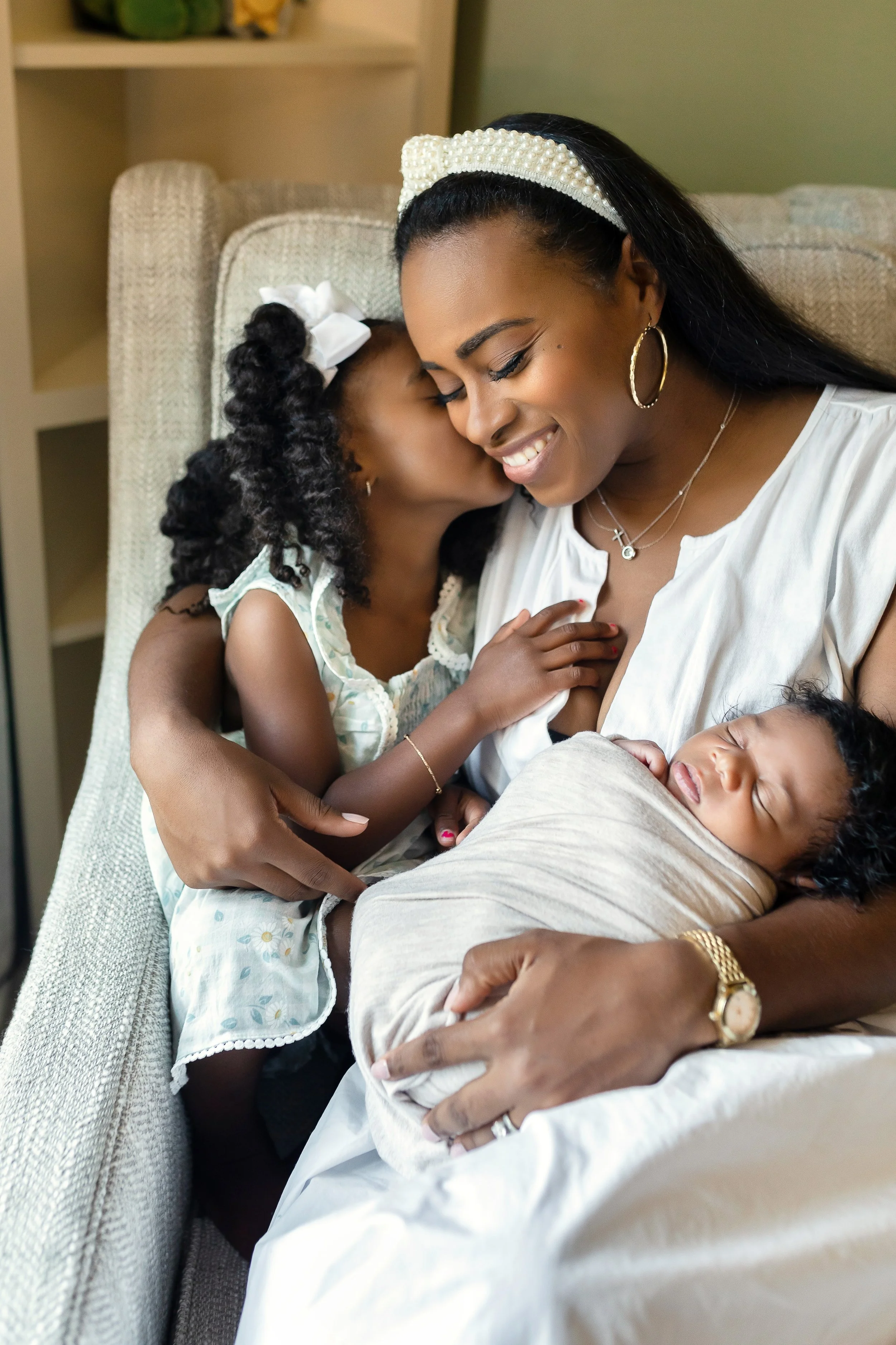Parents cuddling newborn in nursery during lifestyle session.jpeg
