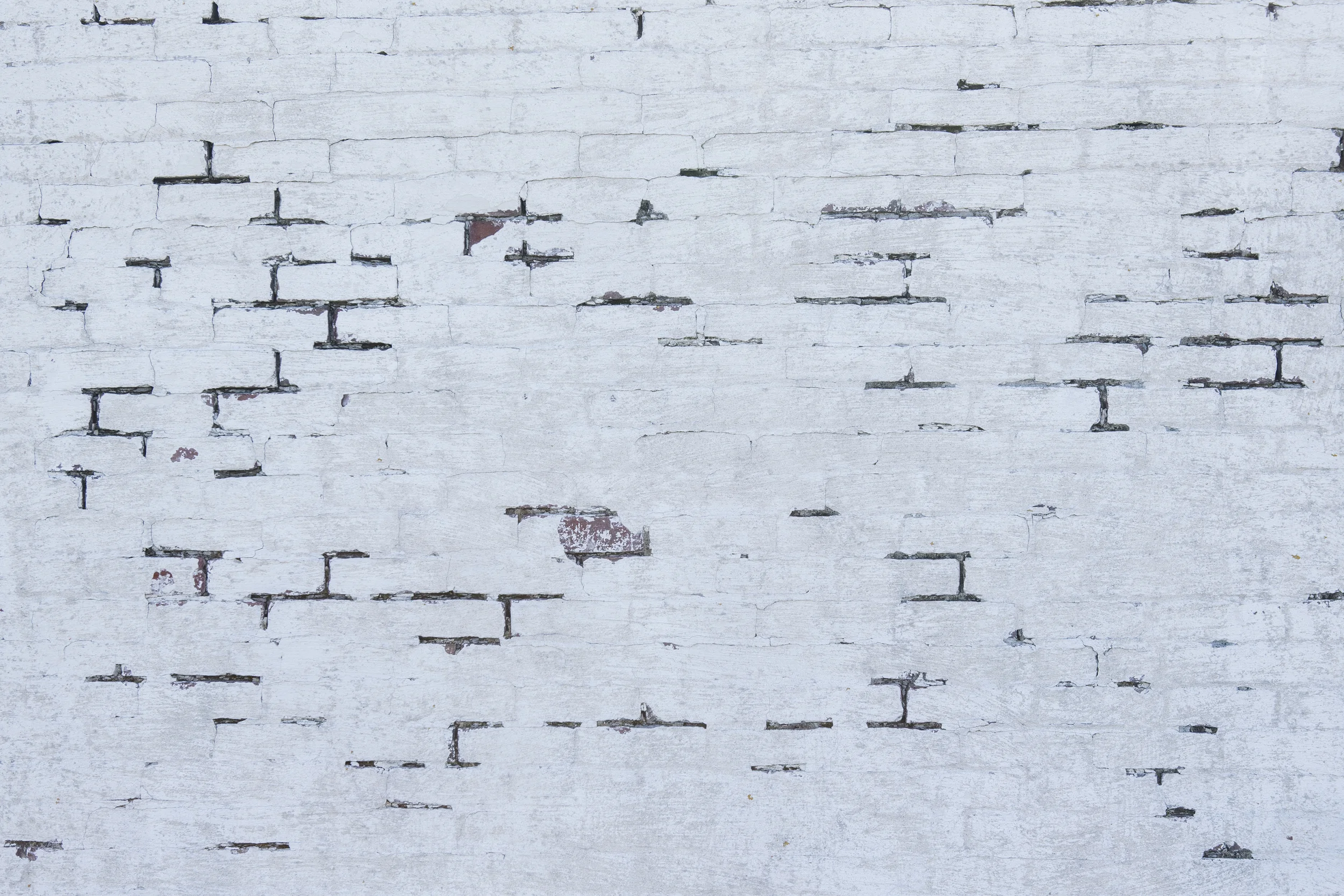 White brick wall with some areas of exposed brick and worn paint