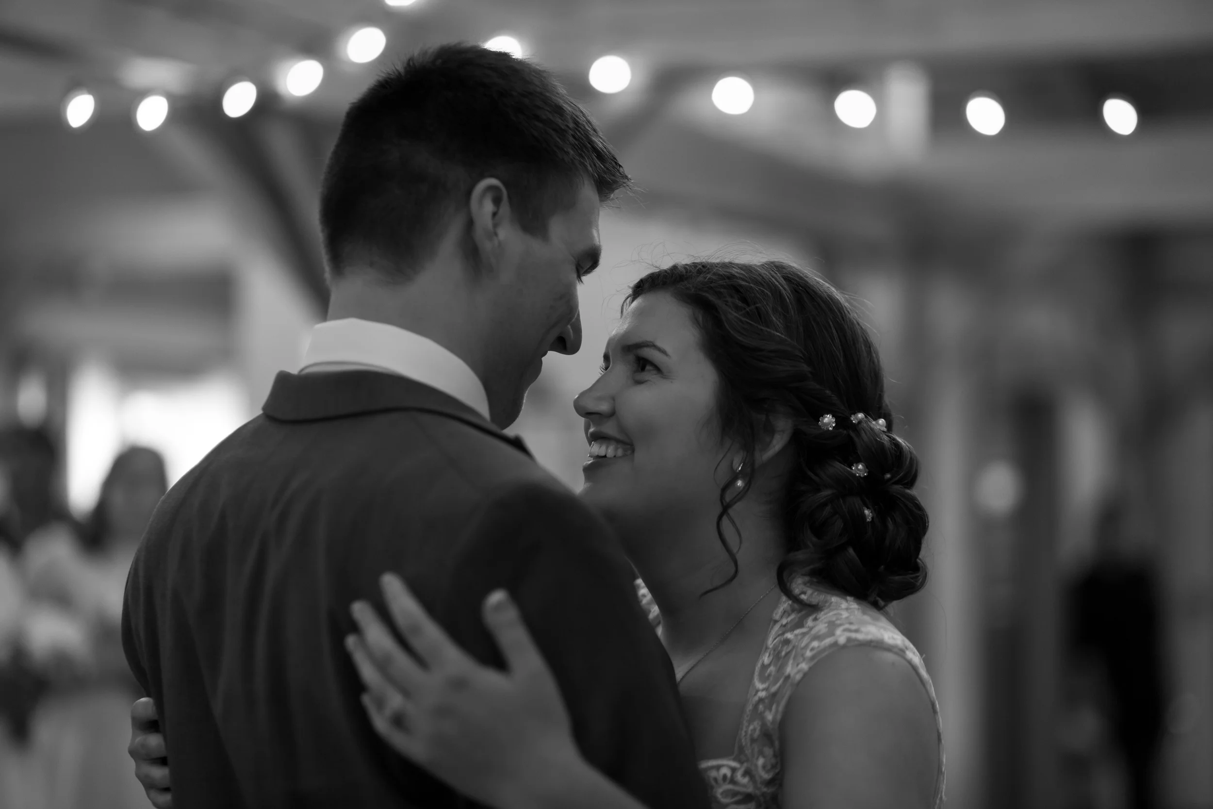 A couple dancing closely at their wedding, smiling at each other, in a black and white photo. hayden budd photo + film new england film photographer