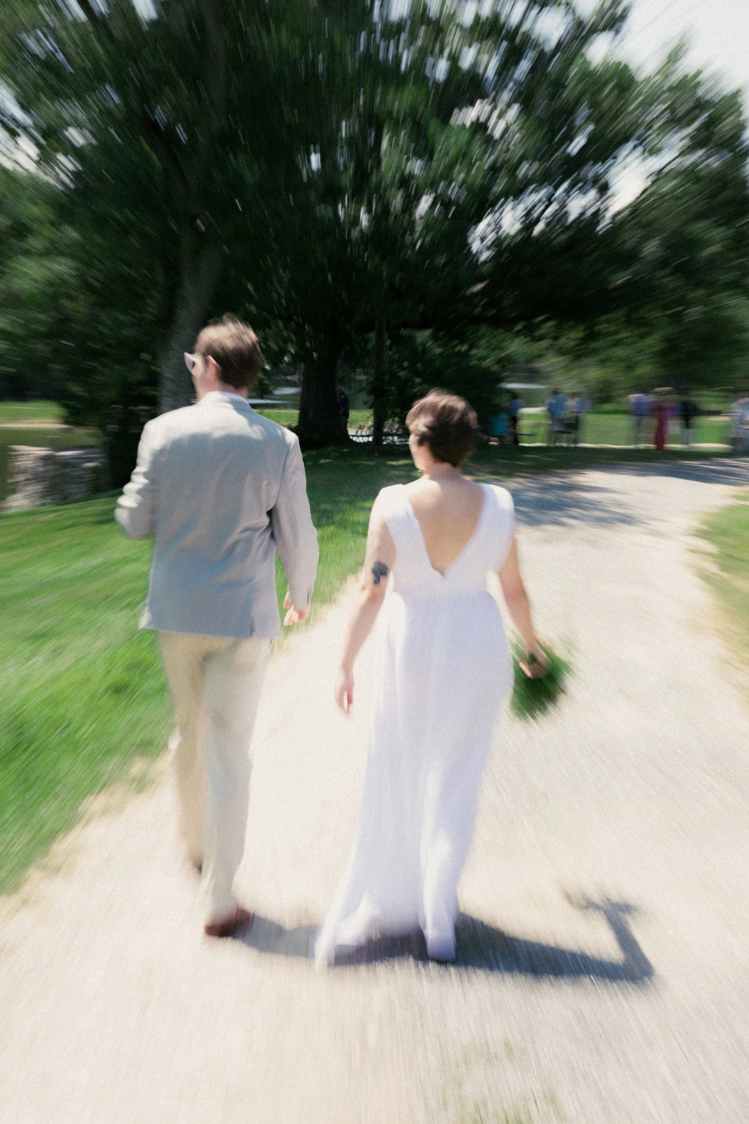 A bride and groom walking together on a sunny day, captured with a motion blur effect around them. hayden budd photo + film new england film photographer