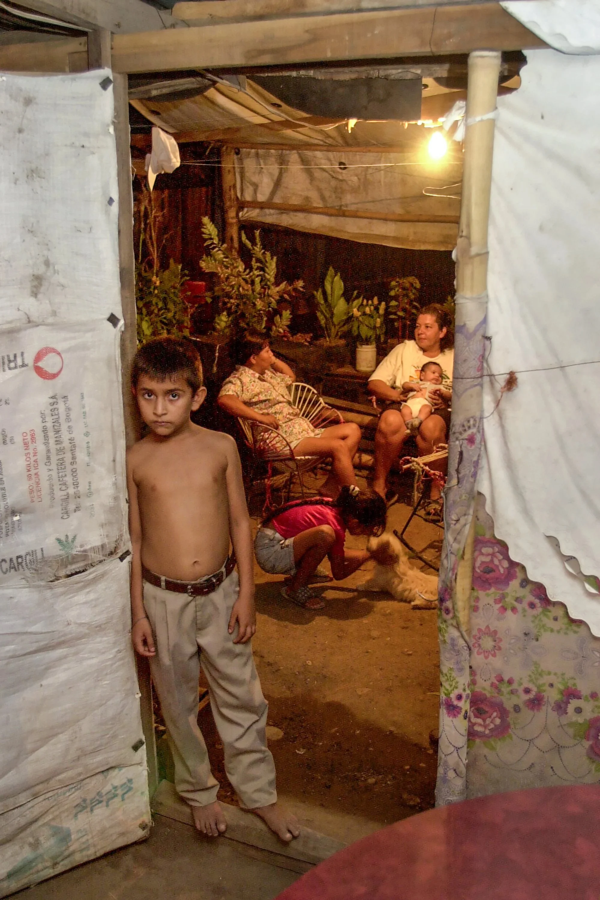  Children and neighbors mingle outside the front door of Hugo Molano's shanty home in the barrio Chicala, outside of Neiva, Colombia. 