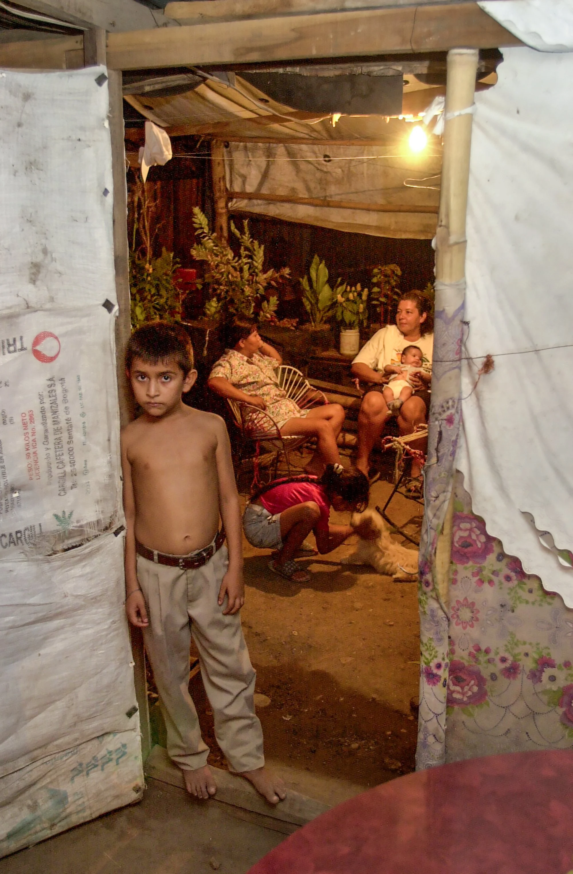  Children and neighbors mingle outside the front door of Hugo Molano's shanty home in the barrio Chicala, outside of Neiva, Colombia. 