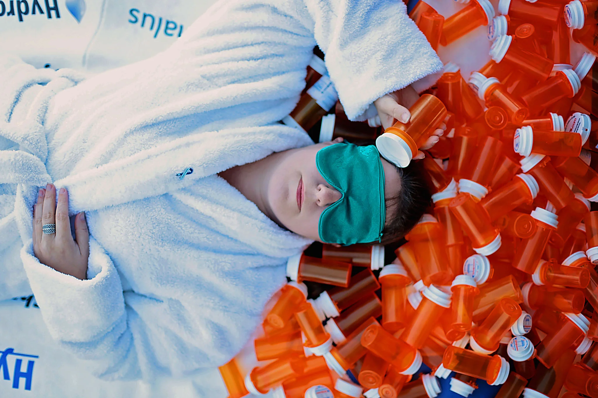 This image depicts life for Sara-Lynn. When the headaches start, it's all she can do to find comfort. Slight comfort can be found by blacking out any light with an eye mask, a comfy robe and a soft blanket. The pill bottles depict life for someone with Hydrocephalus and the many medications they must take to maintain the pain and symptoms.