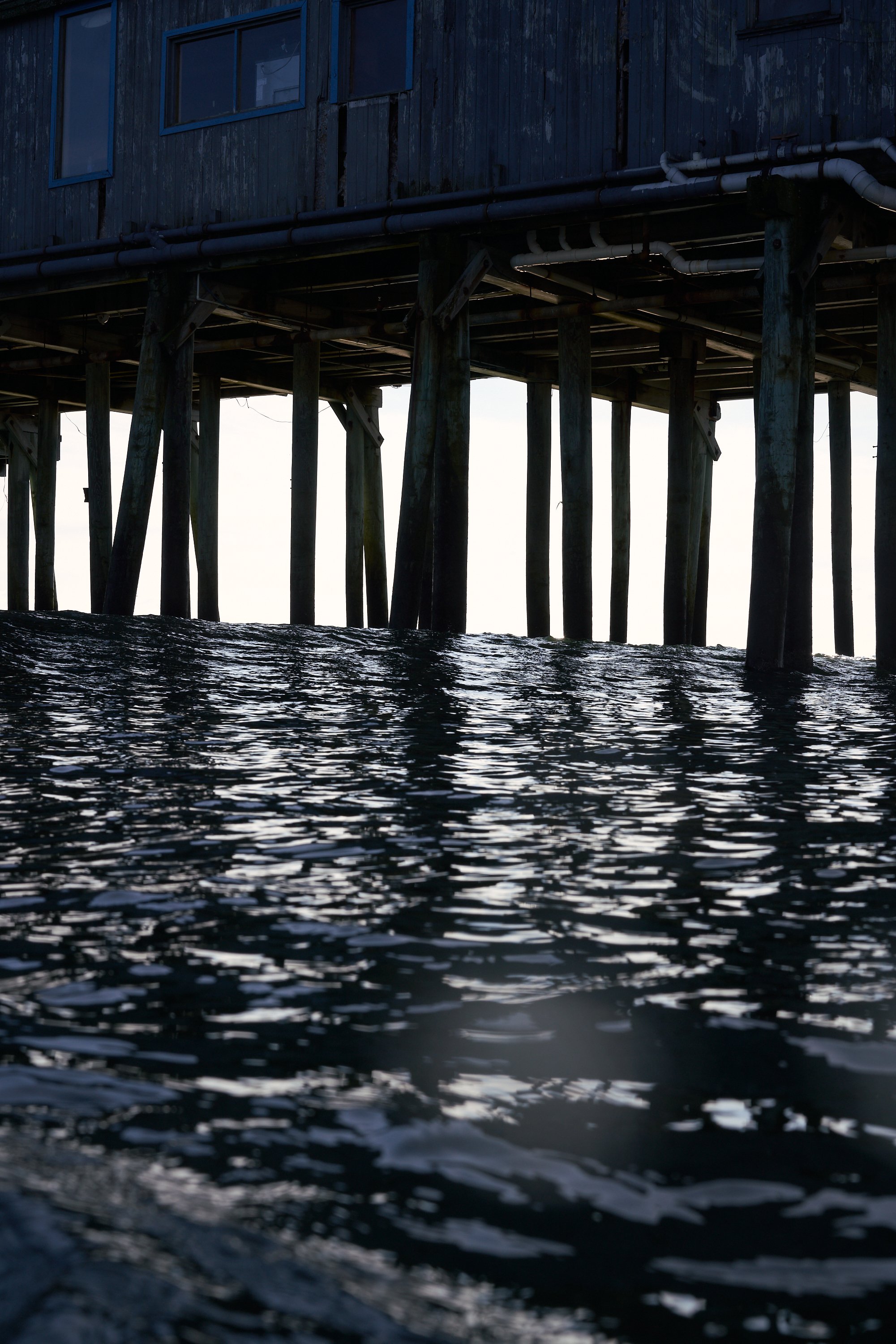 Setting sun behind pier, from the water, surf photography, Ben Macri, Maine