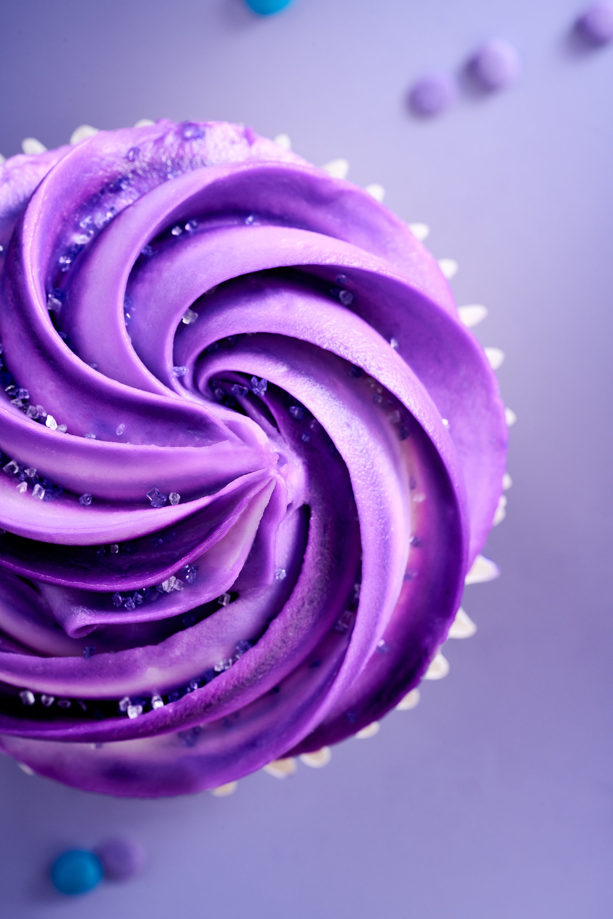 Cupcake with purple frosting, with sprinkles, close up, studio, food photography.