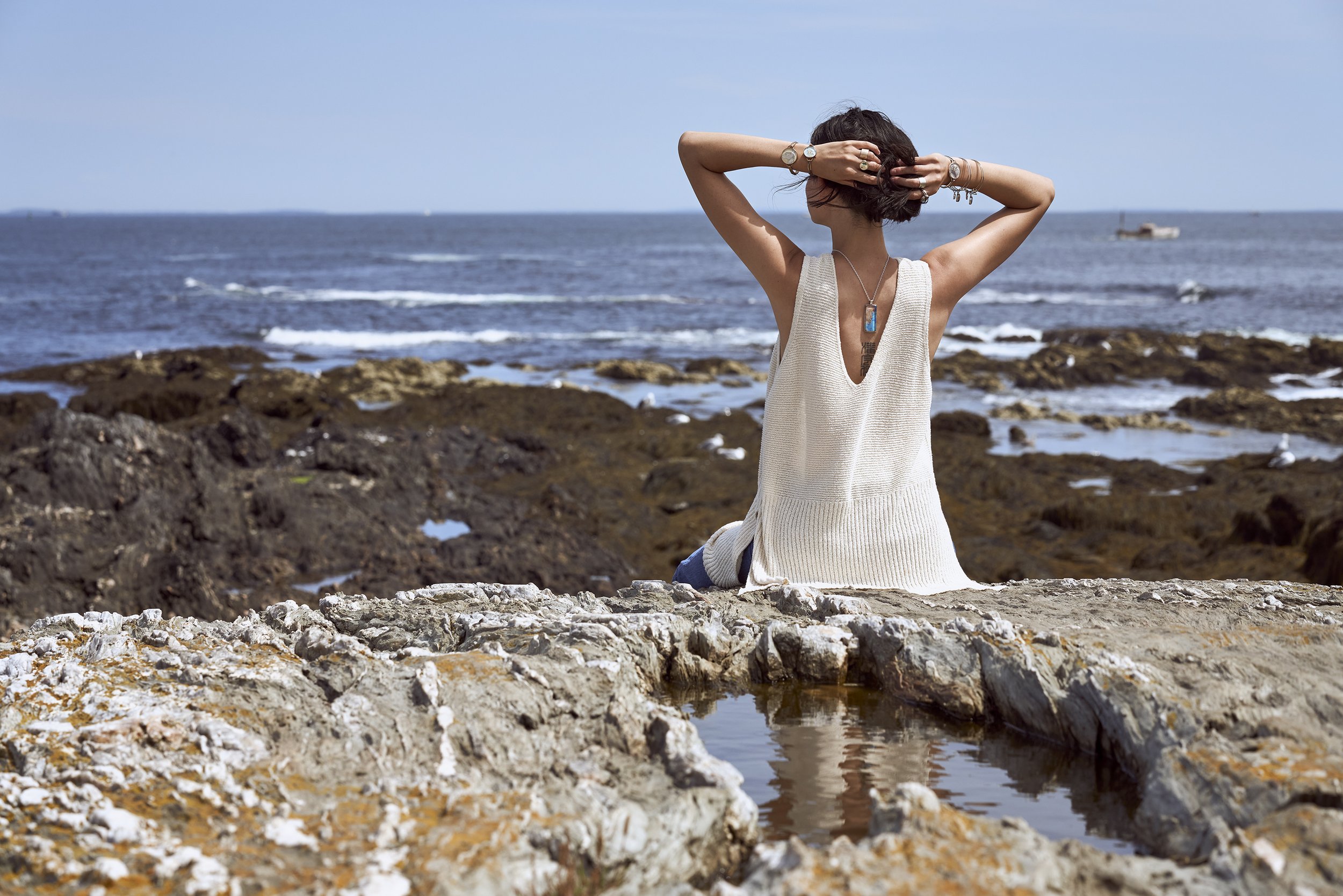A model sitting on a cliff, Chart Metalworks Jewelry, Cape Elizabeth, Maine