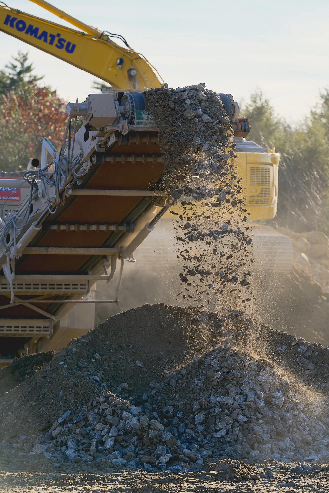 A rock crusher spilling crushed stones, construction, job site photography