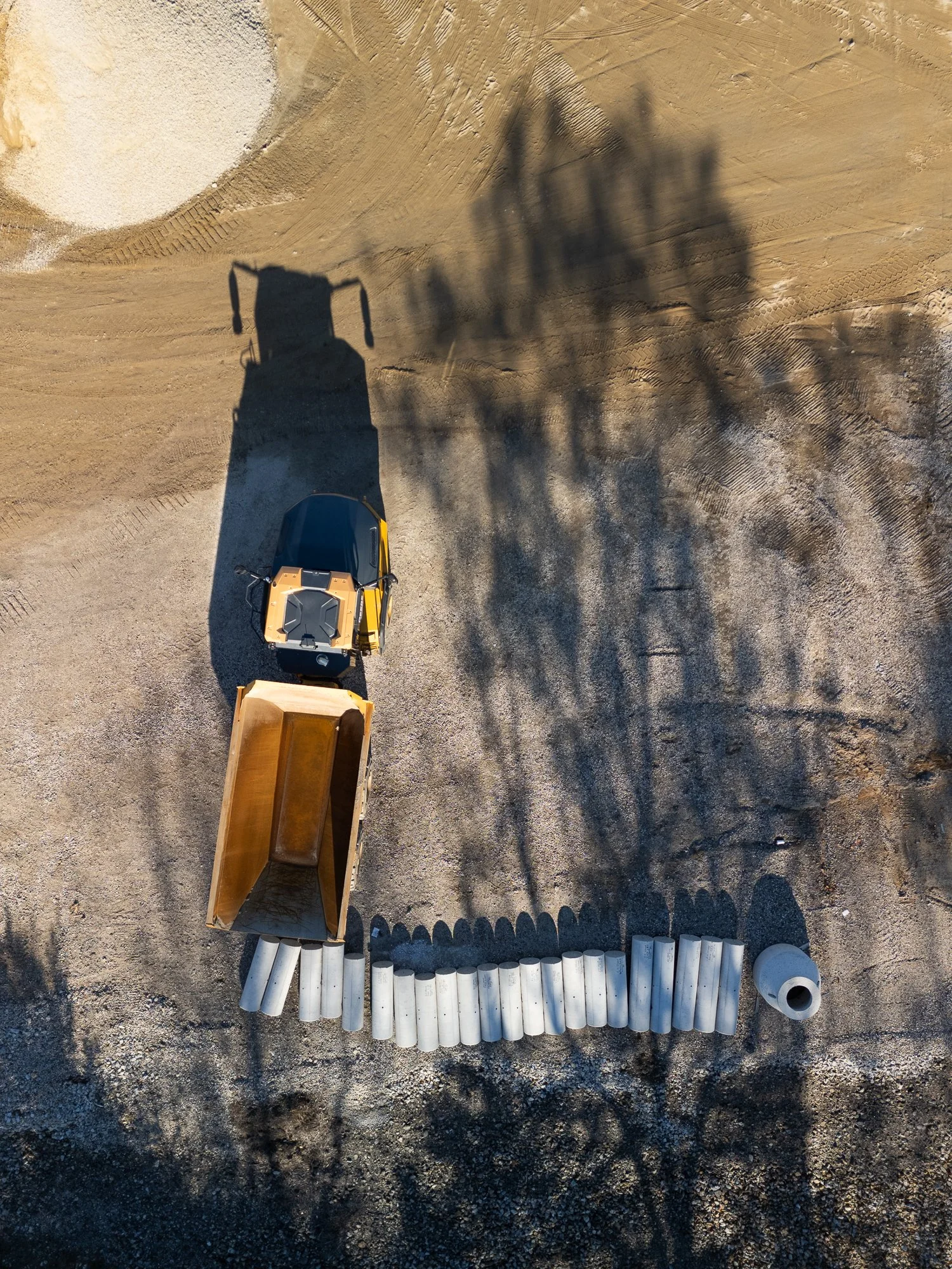 A truck with concrete pipes and shadow, overhead shot from a drone. Construction, drone photography