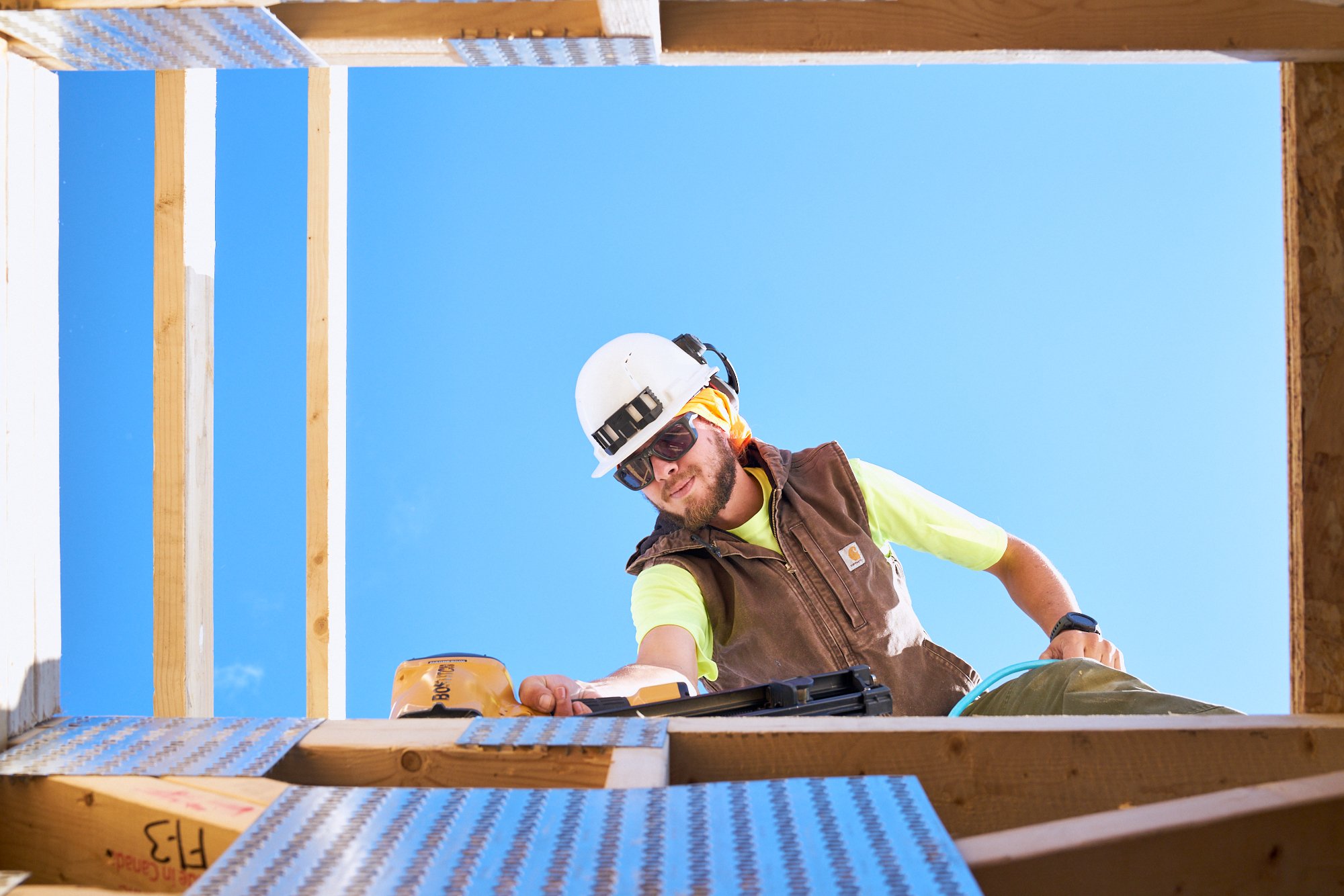 A worker secures a beam with a nail gun, construction photography