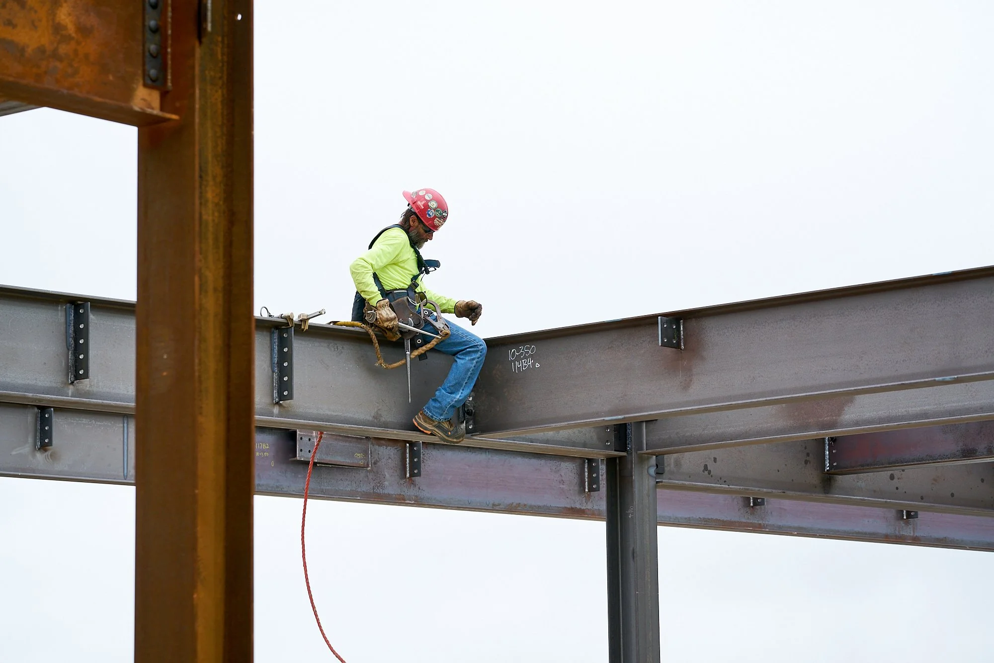 Iron worked sitting atop a beam, construction, jobsite photography