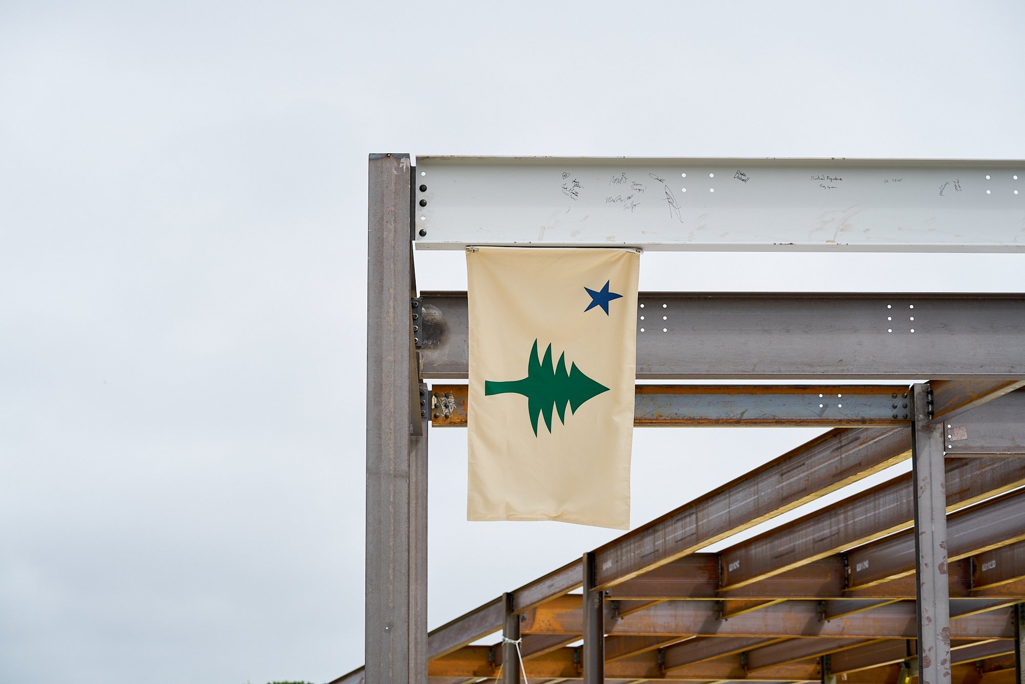 A Maine state flag hanging from steel beams, construction, job site photography