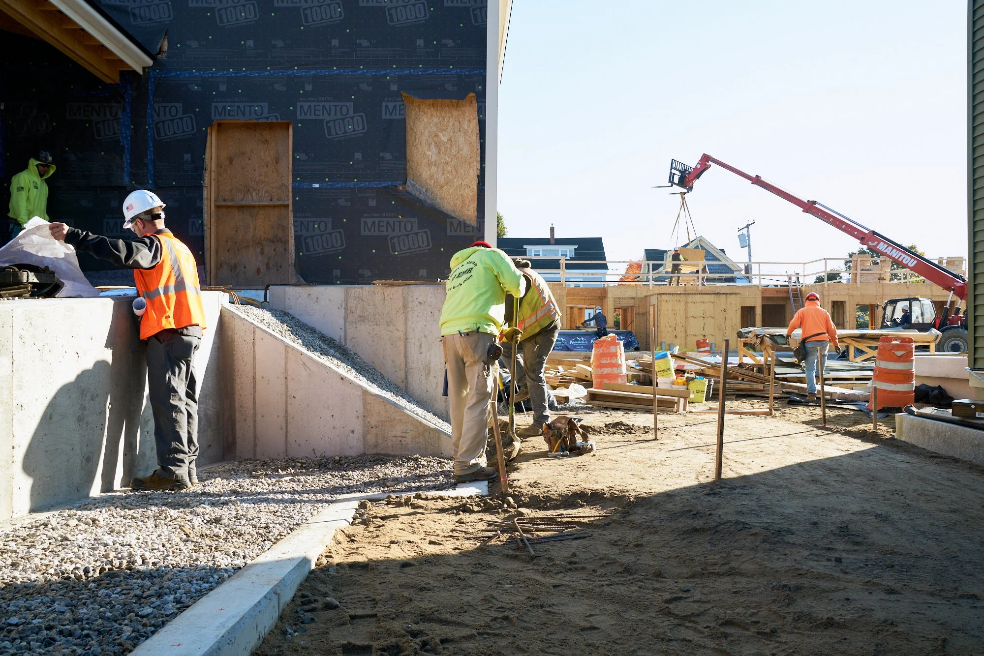 A supervisor consults plans while workers place rebar for a new walkway. Construction photography. Jobsite.