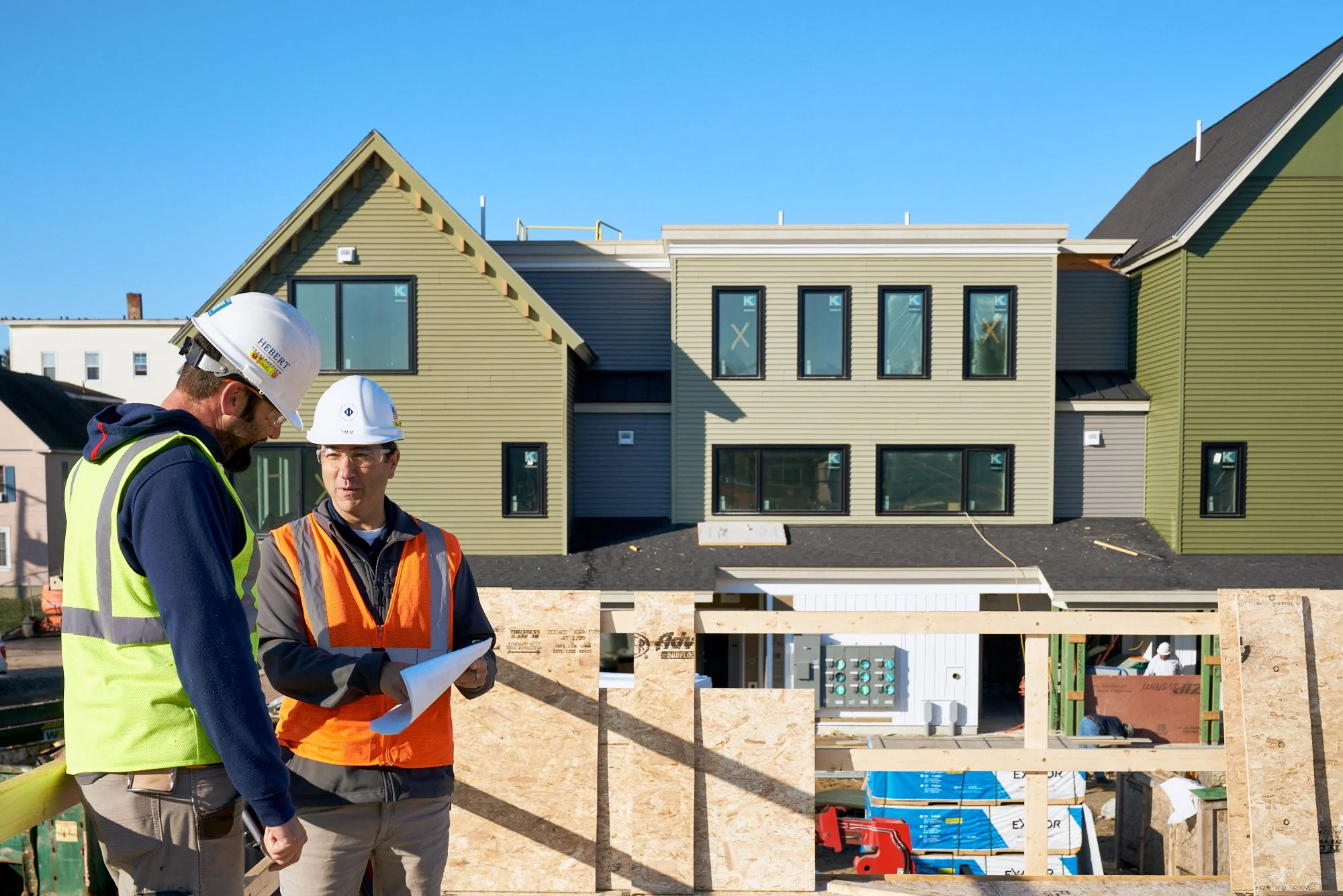 Two supervisors discussing plans, A supervisor looks out at a job site from the second story of a new building. Construction  photography. Candid portrait.